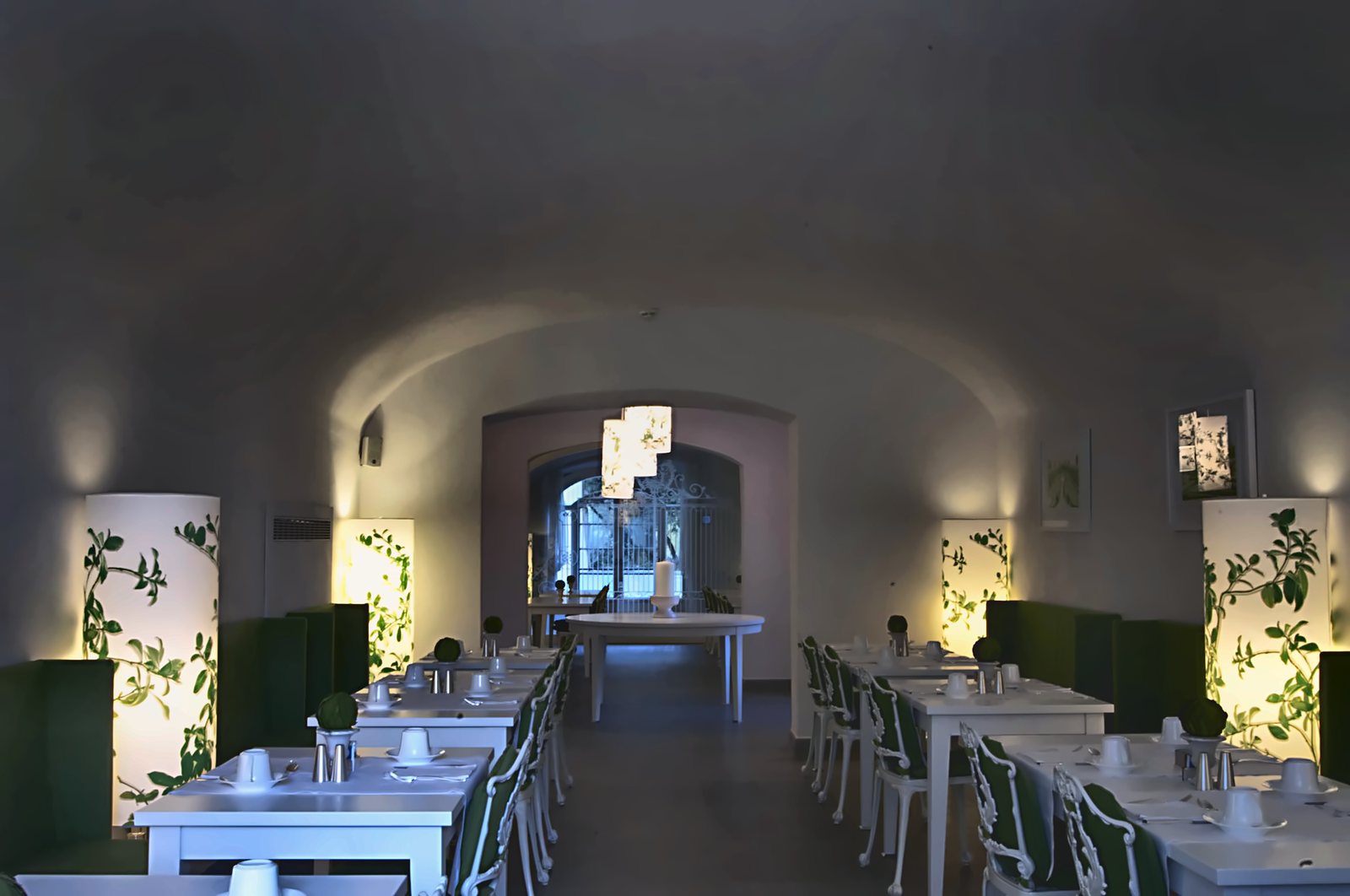 Il ristorante sotto le volte, con le colonne luminose a stampa botanica fra i tavoli