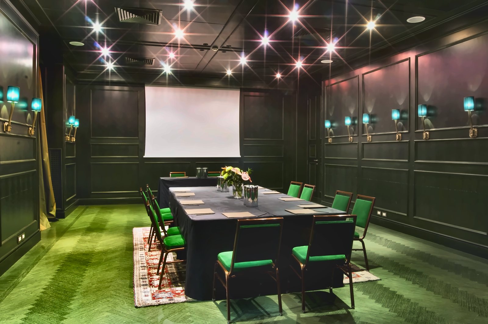 La sala riunioni dell'Aleph: moquette verde, boiserie scura e applique turchesi lungo le pareti
