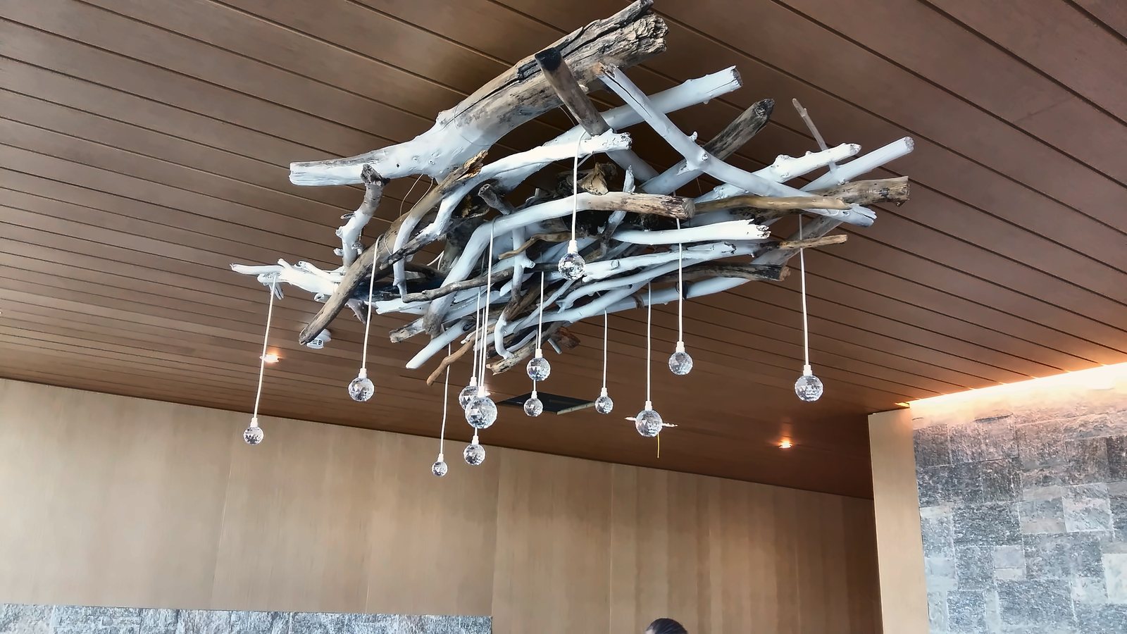 La grappe de gouttes de verre suspendue à une structure de branches, au plafond en bois de l'Alpine Spa