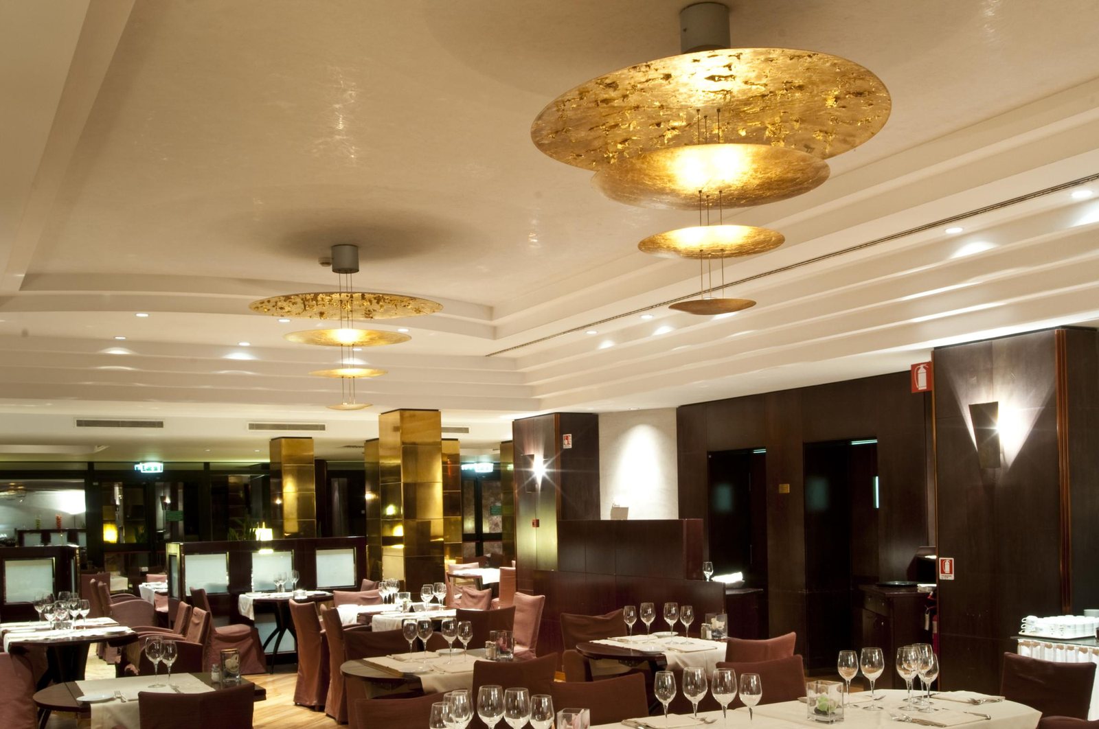 La sala del ristorante apparecchiata, con i dischi dorati sospesi sotto il soffitto
