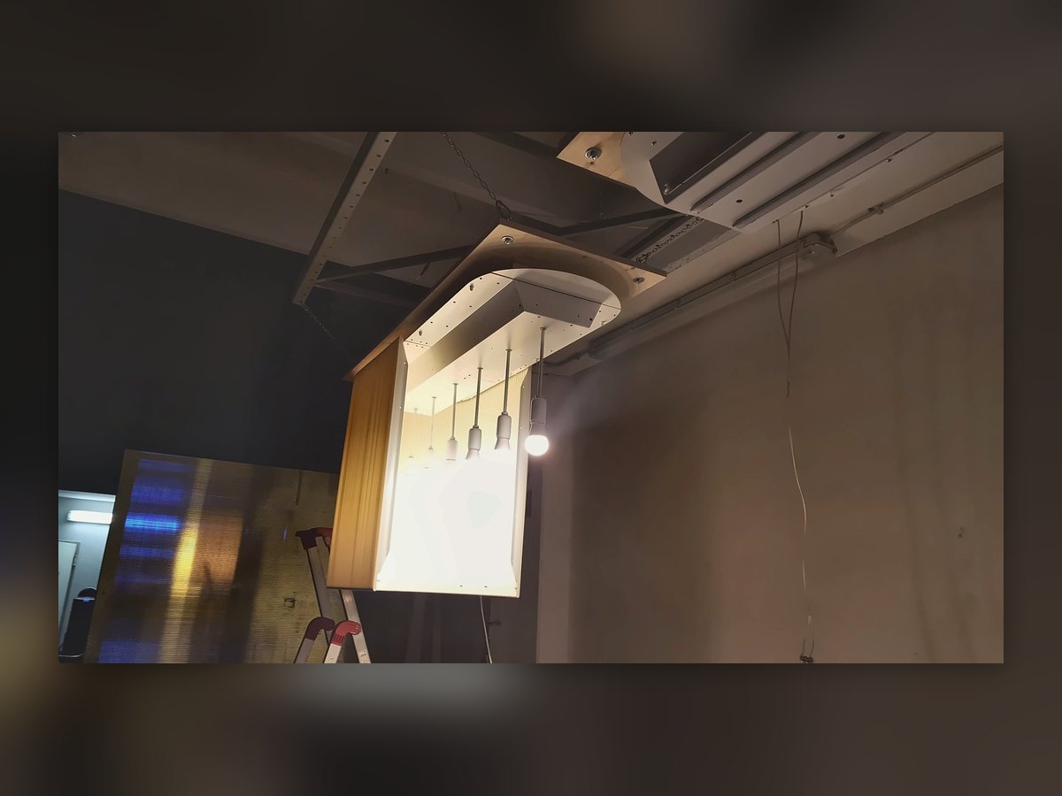 Un paralume plissettato acceso in prova nella nostra officina, appeso alla struttura del capannone