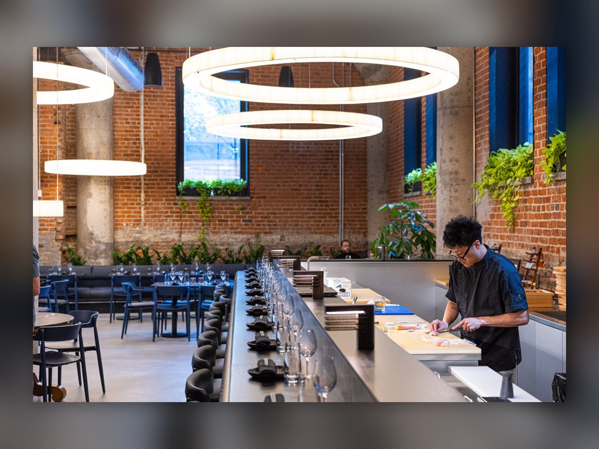 Il banco omakase con il cuoco al lavoro, sotto la coppia di anelli plissettati