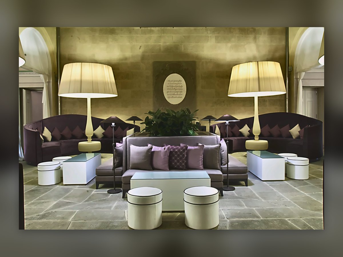 La lounge di Villa Le Maschere con due piantane monumentali dietro i divani