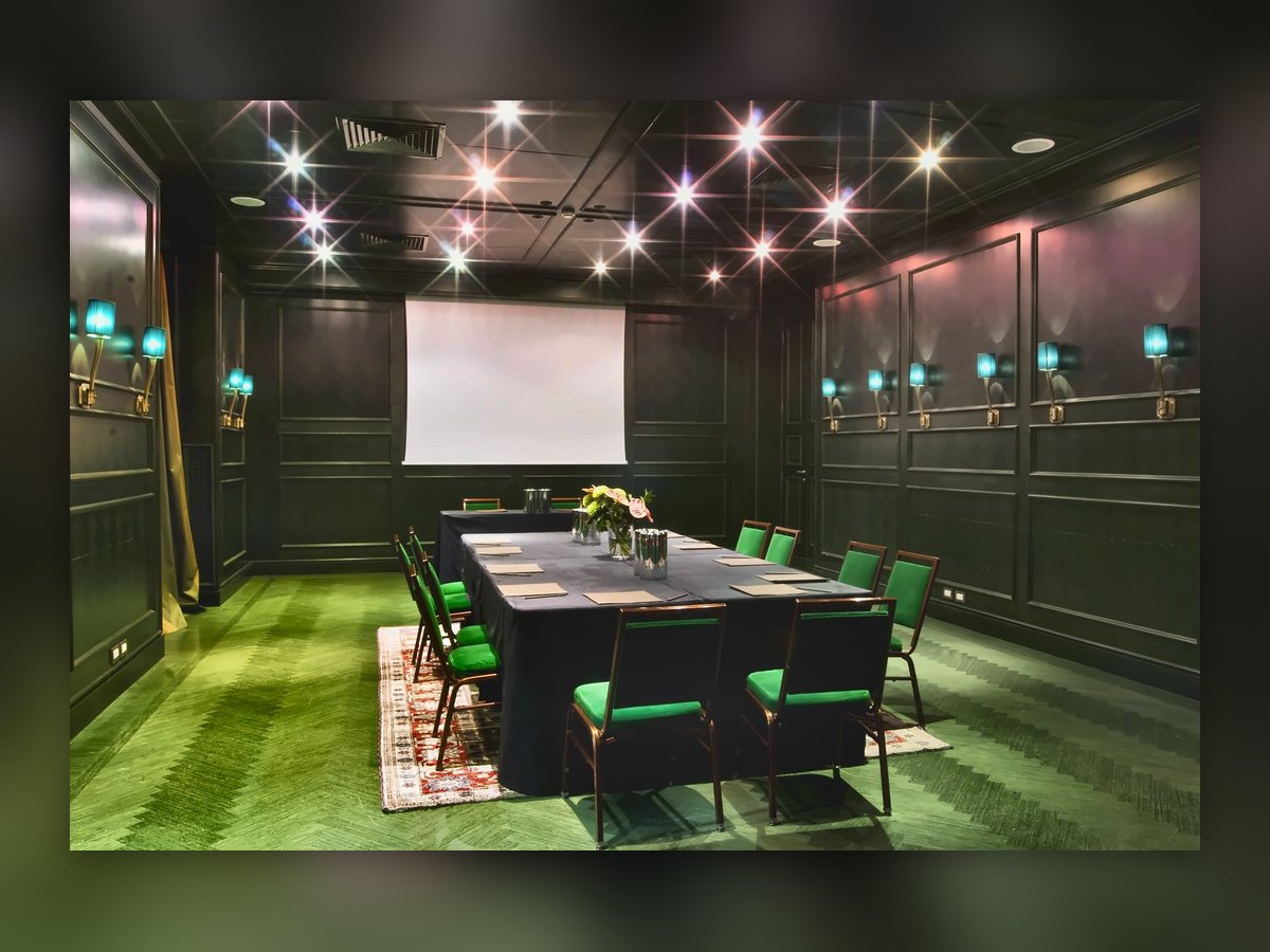 La sala riunioni dell'Aleph: moquette verde, boiserie scura e applique turchesi lungo le pareti