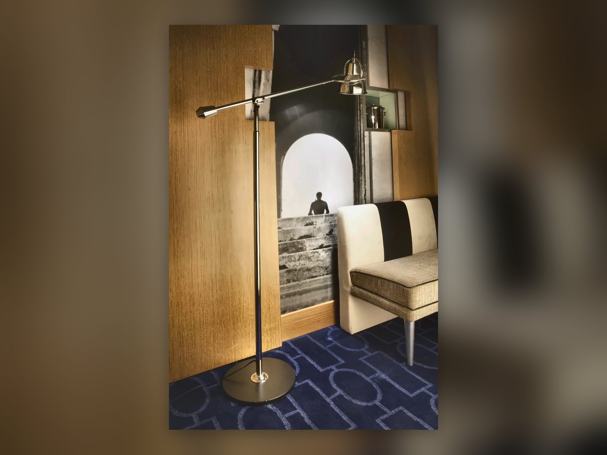 Piantana con braccio articolato cromato nel corridoio con la moquette blu
