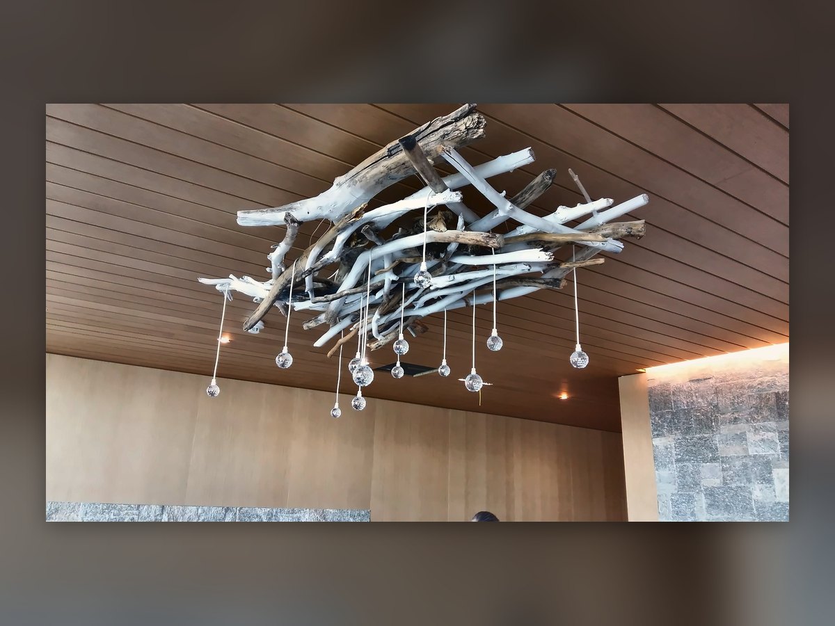 Il grappolo di gocce in vetro appeso a una struttura di rami, sul soffitto in legno dell'Alpine Spa