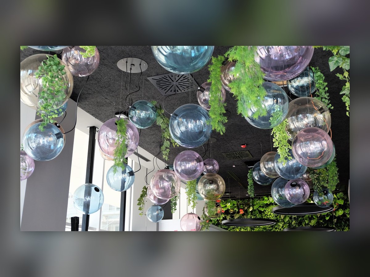 Il grappolo di sfere in vetro colorato e specchiato visto dal basso, con le piante che scendono fra una sfera e l'altra