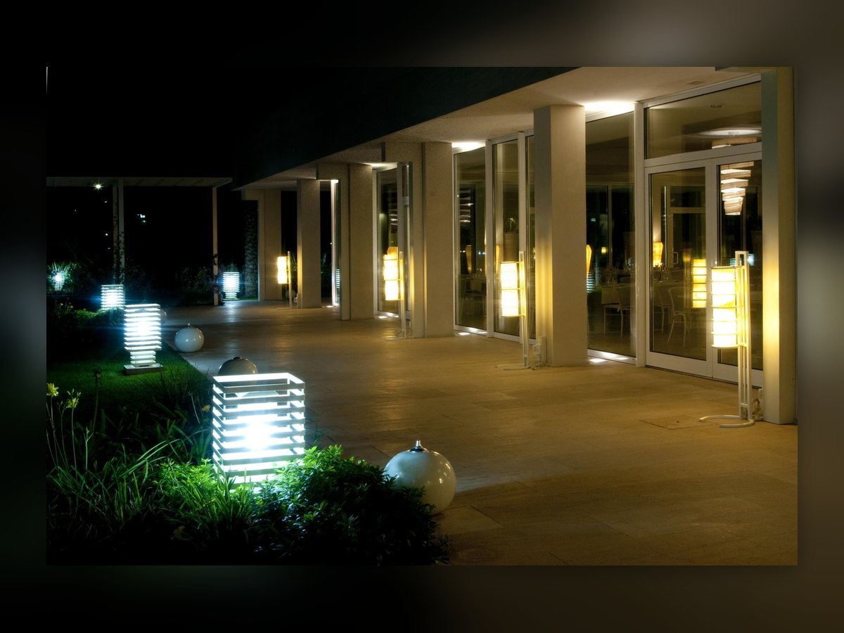 Il portico di notte: il paletto acceso in primo piano e la fila di luci lungo le vetrate