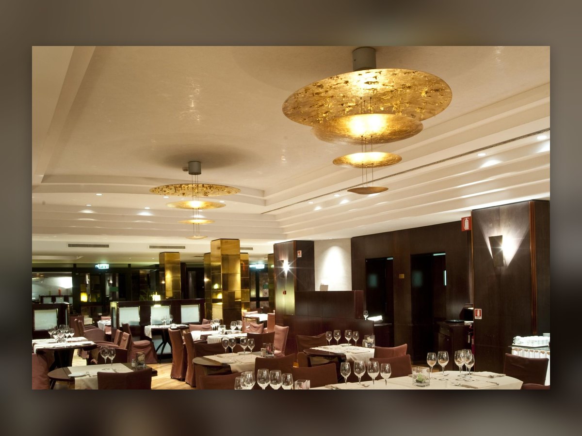 La sala del ristorante apparecchiata, con i dischi dorati sospesi sotto il soffitto
