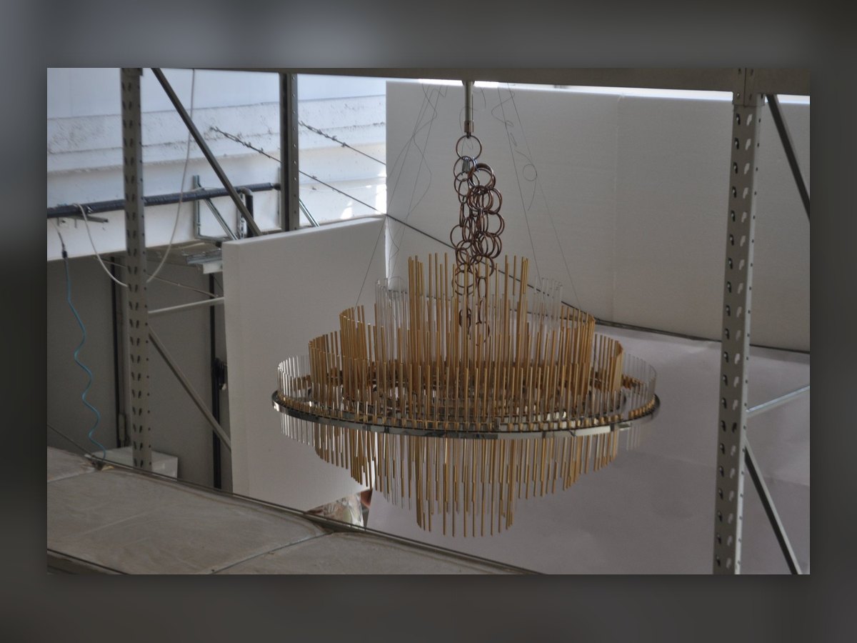 Il lampadario appeso in officina per la prova, davanti a un fondale bianco
