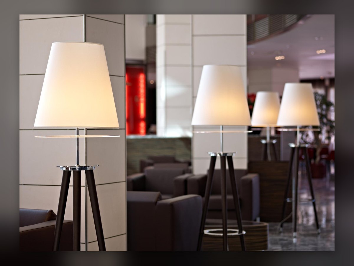Le hall de l'Antony Palace Hotel : quatre lampadaires tripodes à abat-jour blanc entre les fauteuils sombres et les piliers