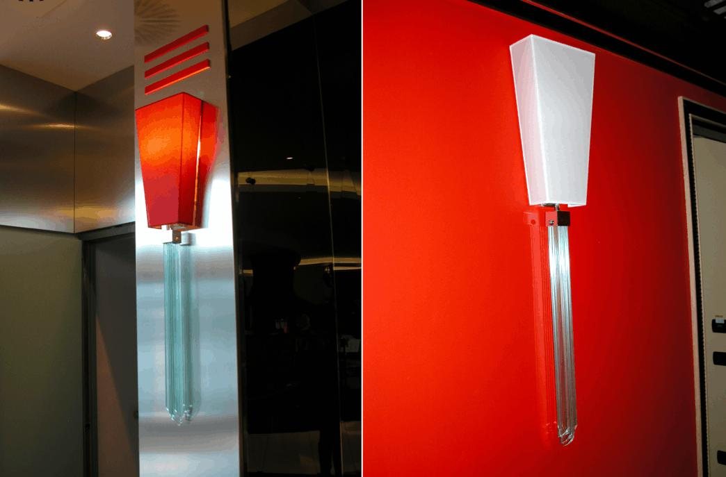 L'applique de l'UNA Hotel Malpensa en deux vues : abat-jour rouge sur le pilier habillé de métal, blanc sur le mur rouge, sur une pampille de losanges de cristal