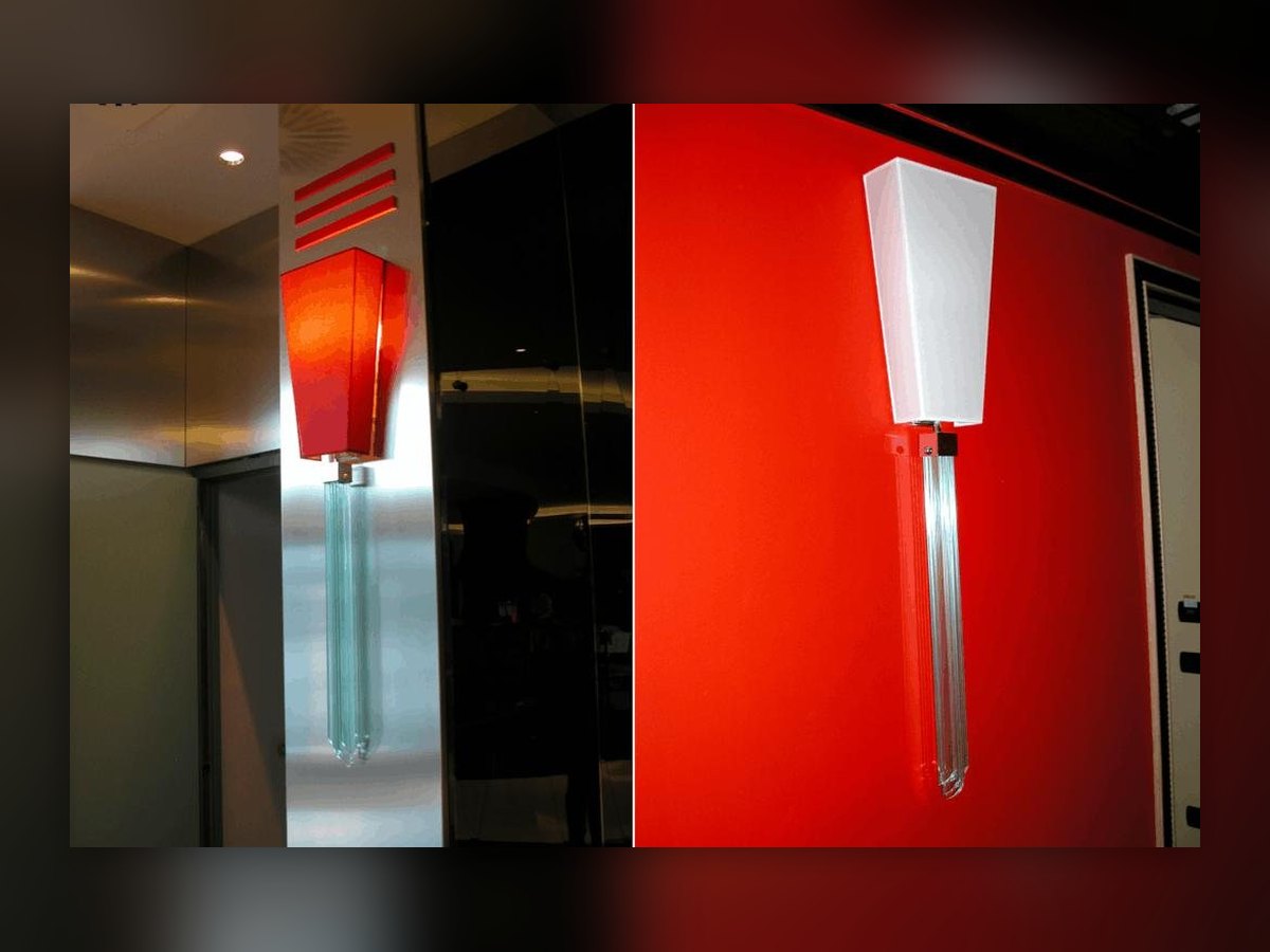 L'applique de l'UNA Hotel Malpensa en deux vues : abat-jour rouge sur le pilier habillé de métal, blanc sur le mur rouge, sur une pampille de losanges de cristal