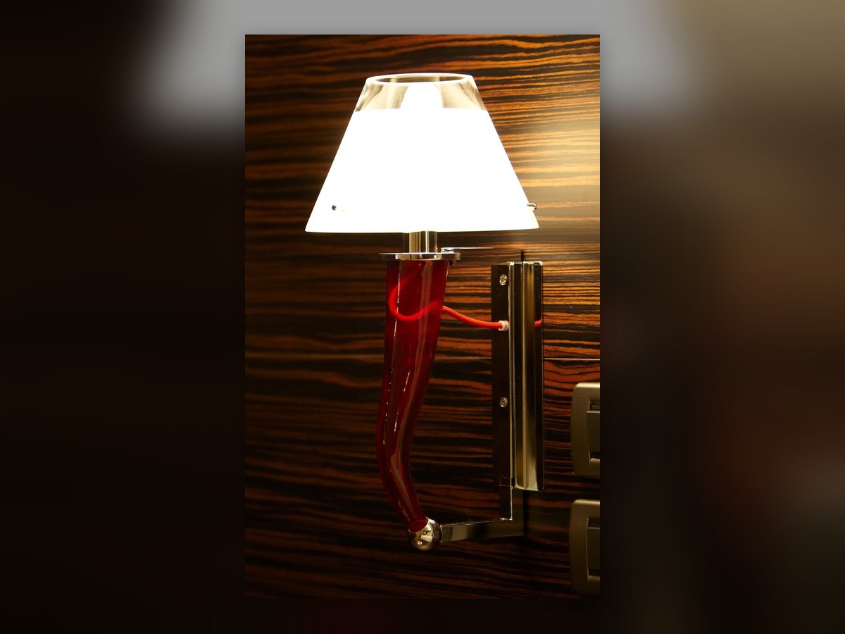 Wandleuchte im Antony Palace aus der Nähe: rotes Glashorn und weißer Schirm auf dunkler Holzverkleidung