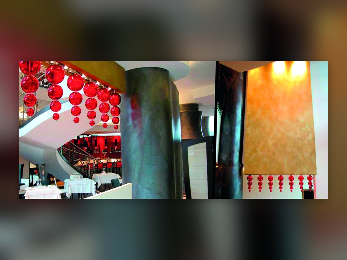 Les sphères rouges en verre soufflé de l'UNA Hotel Malpensa en deux vues : au-dessus de l'escalier hélicoïdal et en rangée sous un panneau doré