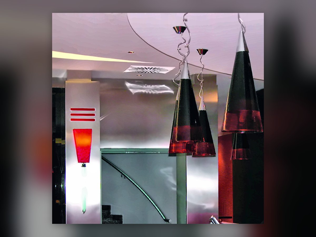 Les cônes en verre soufflé noir et rouge au-dessus de la réception de l'UNA Hotel Malpensa, et l'applique rouge sur le pilier en acier