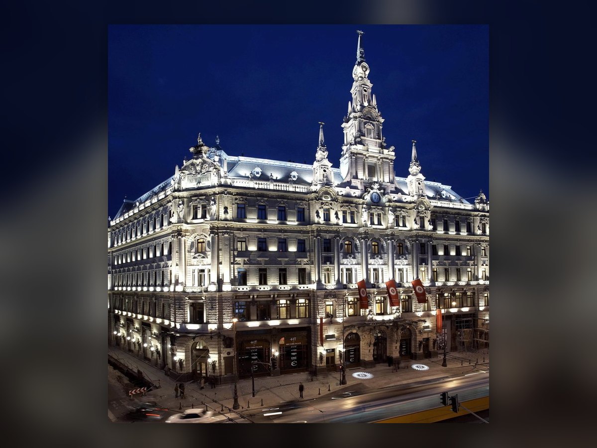 Das New York Palace nachts von oben an der Ecke gesehen: beide Fronten beleuchtet und der Mittelturm