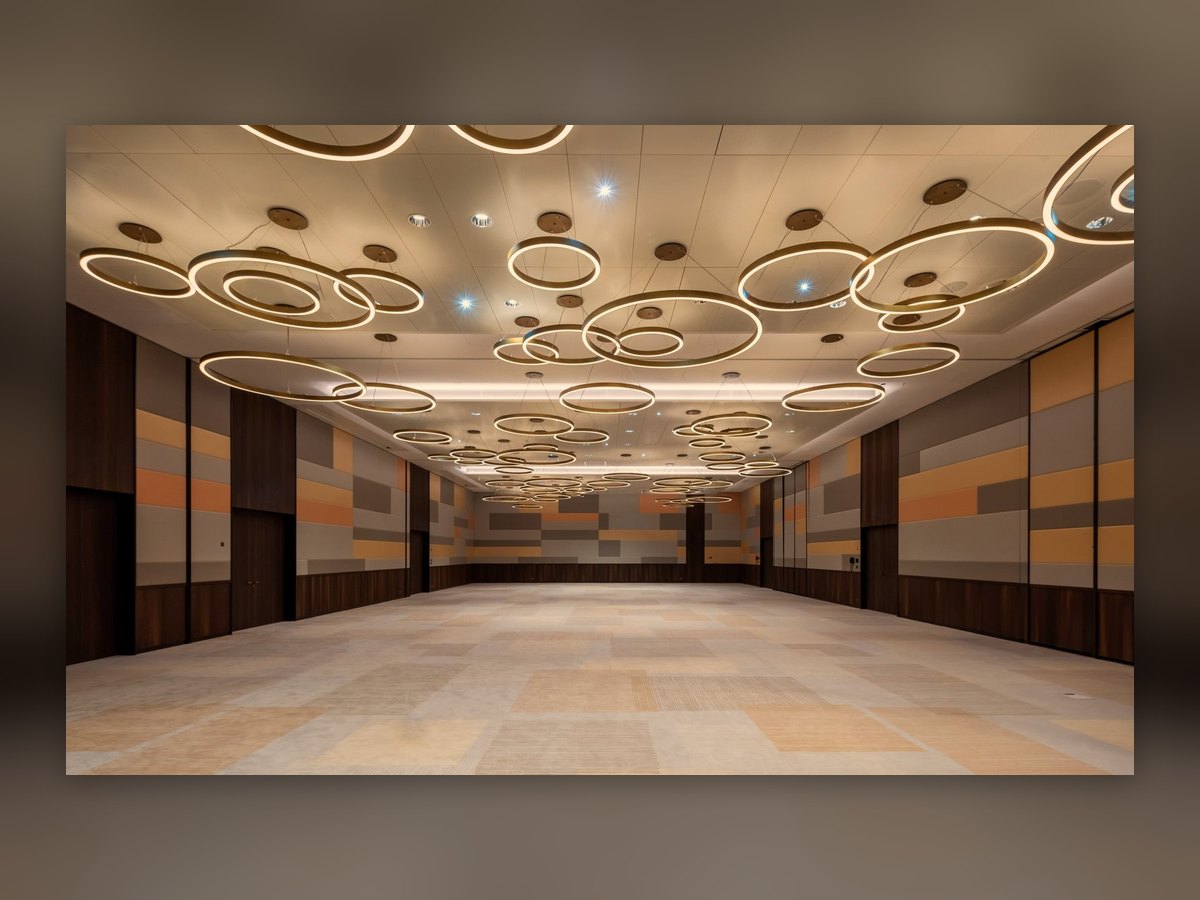 The empty ballroom of the Mövenpick Hotel Basel: glowing brass-coloured rings of different sizes hung at different heights under the ceiling, walls in grey and orange bands