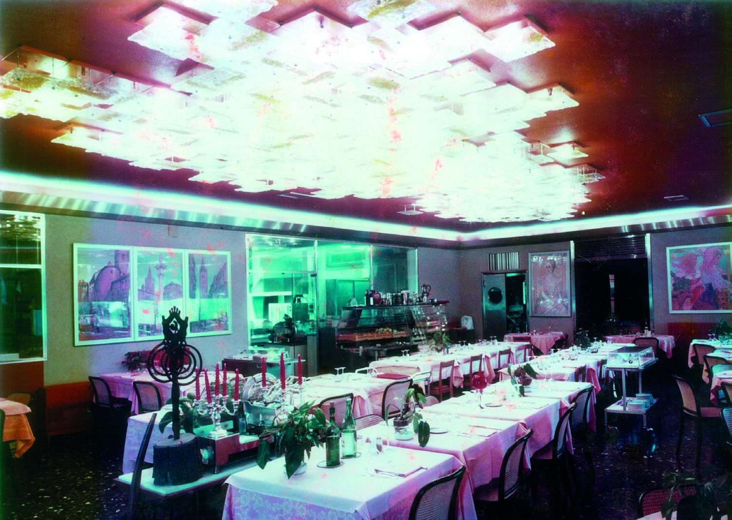 Il ristorante del Russott Hotel ai tempi dell'Hotel Ramada: una composizione di piastrelle di vetro trasparente e ambra accesa sul soffitto, sopra i tavoli apparecchiati con tovaglie rosa